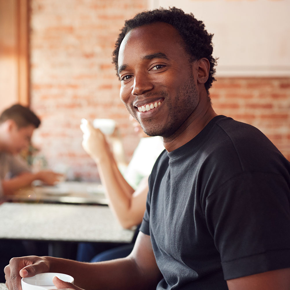 portrait-of-smiling-man-sitting-at-table-in-coffee-X7YY6PU.jpg