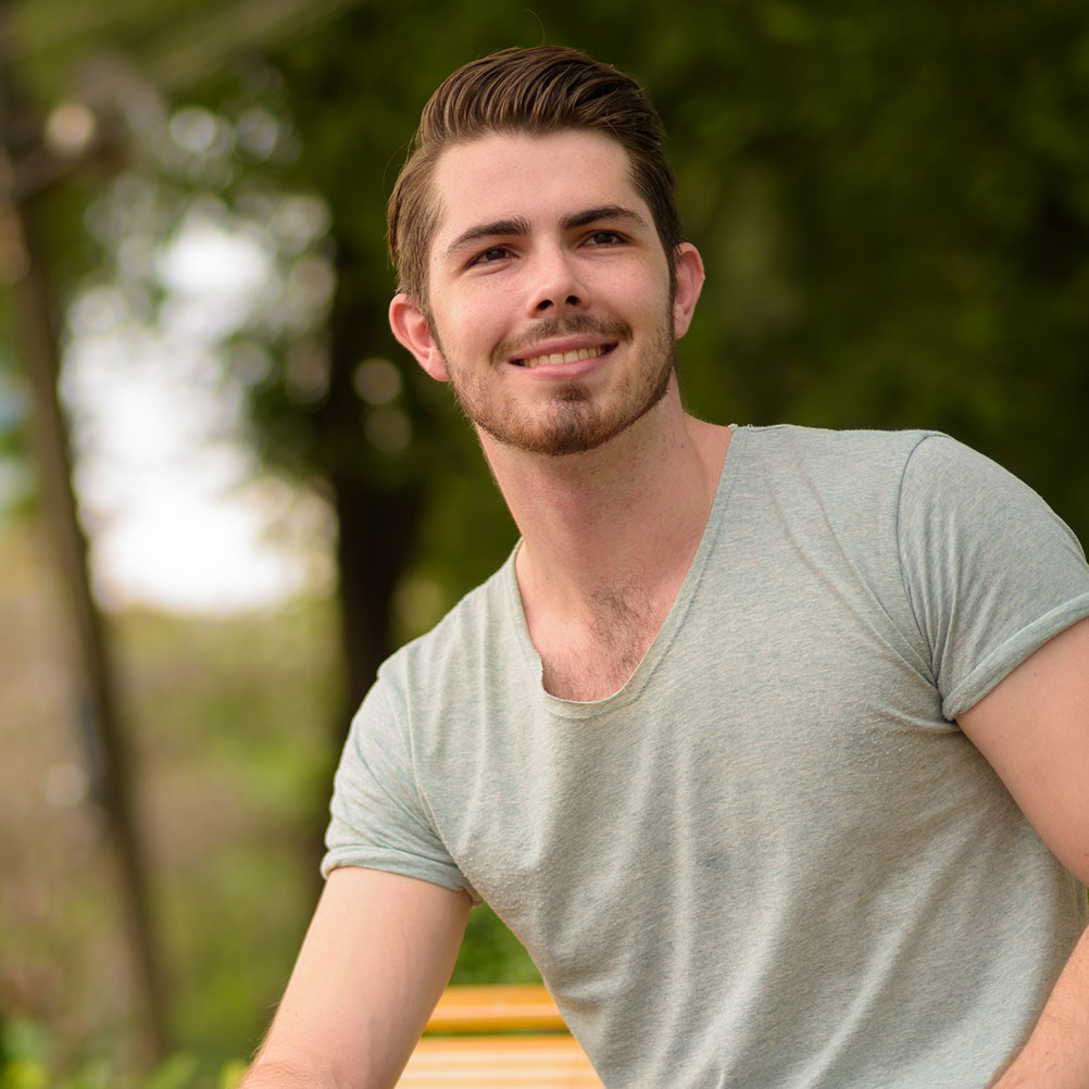 portrait-of-young-handsome-man-sitting-at-park-whi-FLVG4K4.jpg